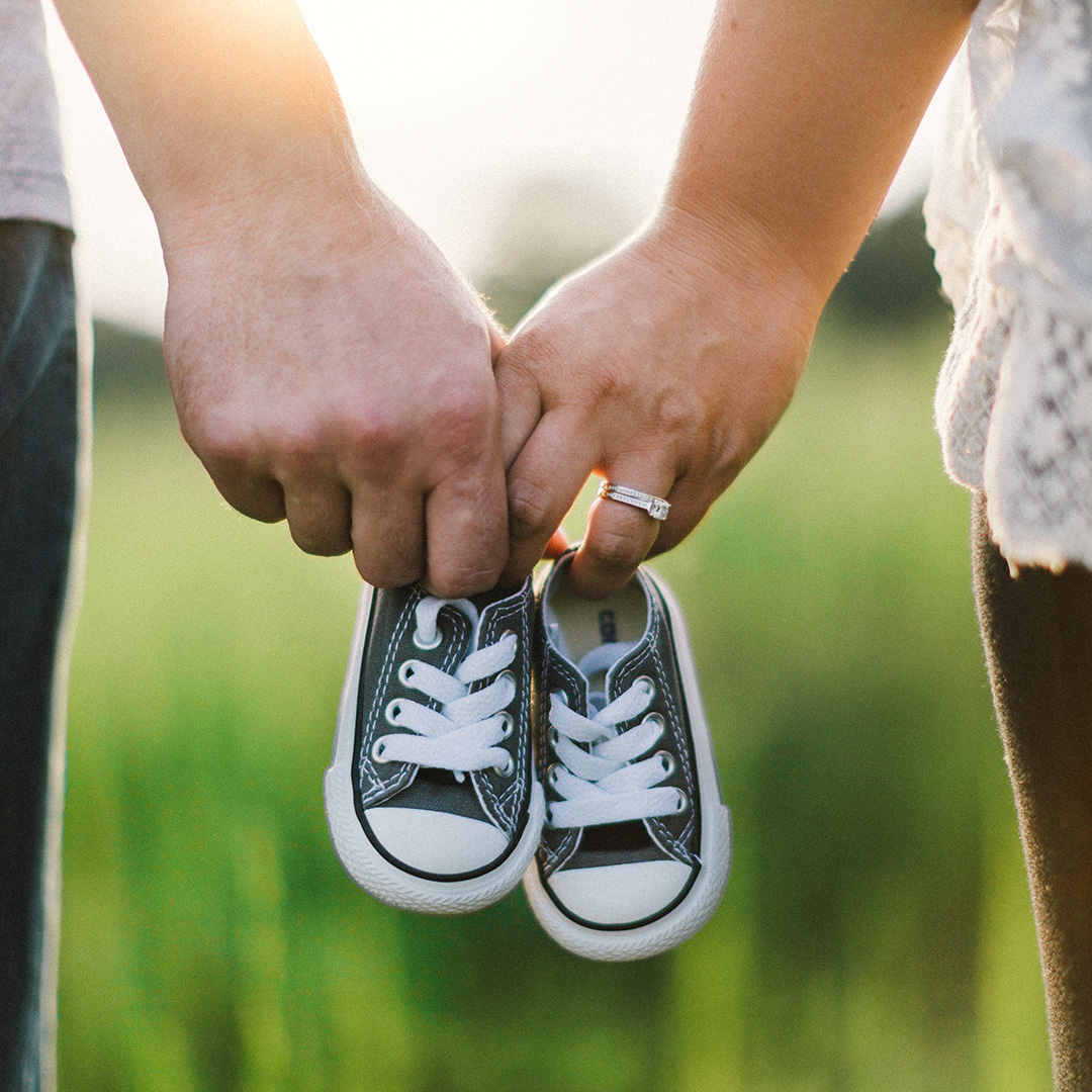 Baby shoes and couple holding hands